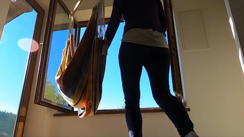 A Woman Sits On A Hammock By The Window