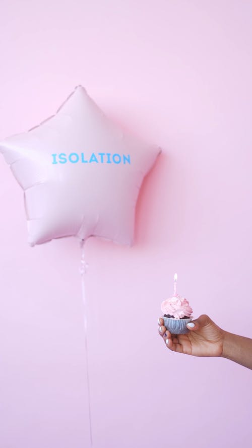Hand Holding a Cupcake near a Balloon