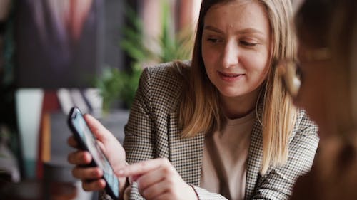 A Woman Showing Something on her Mobile Phone