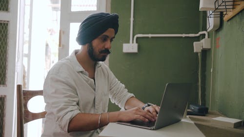 A Man Using a Laptop while a Woman is Watching Him