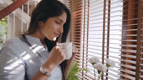 A Woman Smelling Her Coffee In The Morning