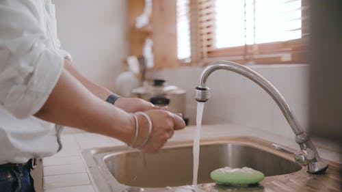 A Man Washing His Hands in the Kitchen Sink