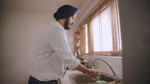 A Man Washing His Hands in the Kitchen Sink