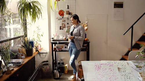 A Woman Having Coffee While Looking At  Her Indoor Plants