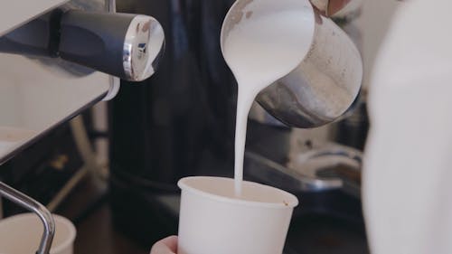 A Person Pouring Milk Froth into the Cup