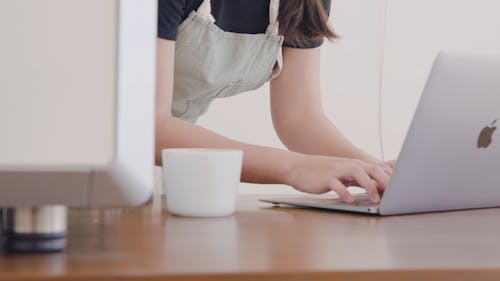 A Woman Using A Laptop While Wearing An Apron