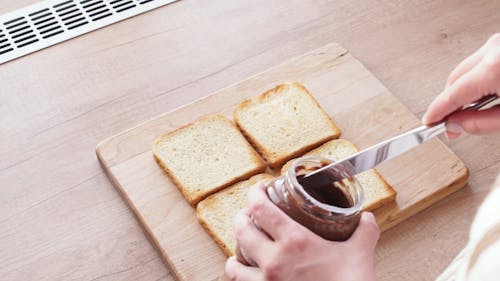 A Person Spreading Chocolate Butter on the Bread