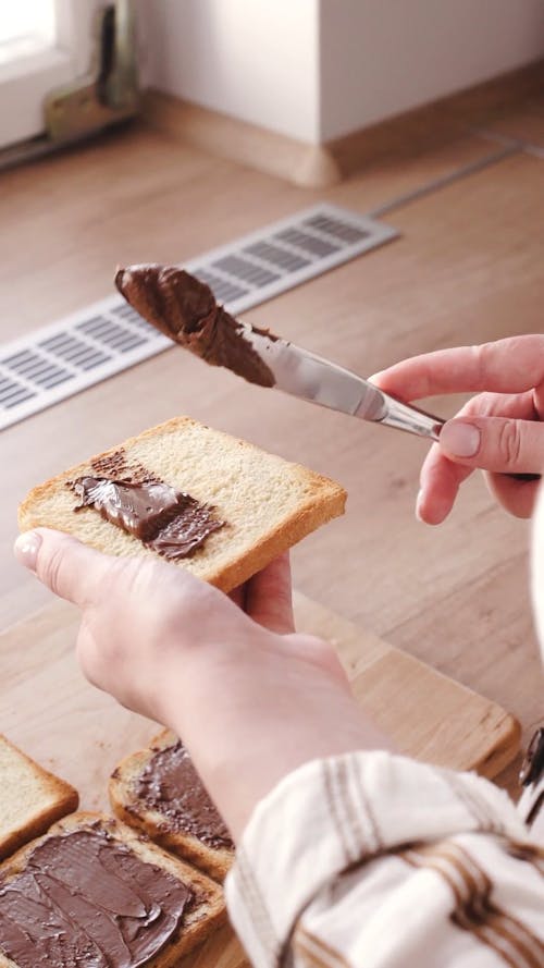 A Person Spreading Chocolate Butter on the Bread