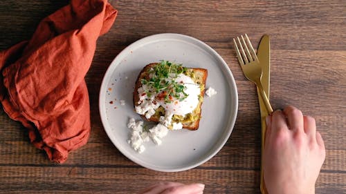 A Person Slicing the Egg on the Bread