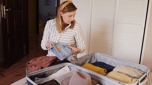 A Woman Packing Clothes In A Suitcase