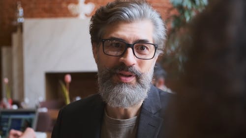 Man Drinking Coffee while Talking to a Person