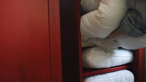 Person Putting Blanket on the Cabinet 