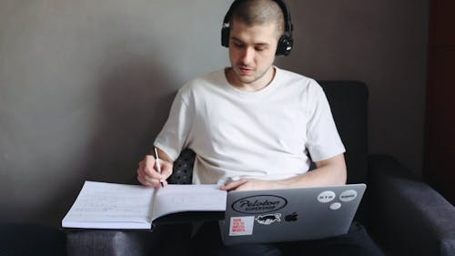 A Man Taking Notes While in Front of the Computer