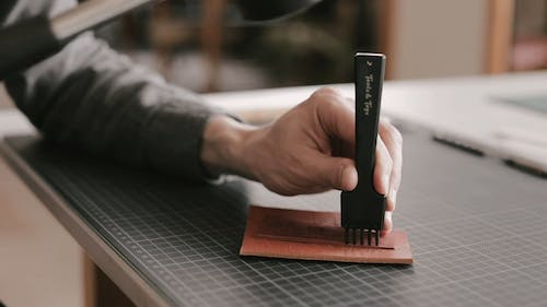 A Person Using a Diamond Chisel on a Piece of Leather