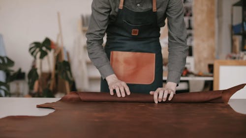 Man Rolling A Leather Sheet