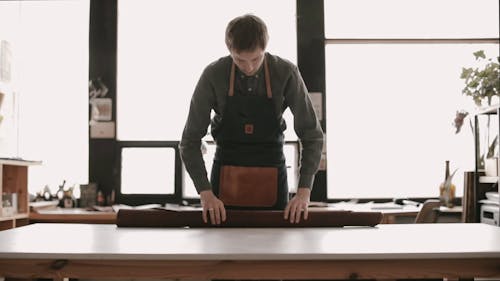 A Leather Worker Rolling Out The Leather Material