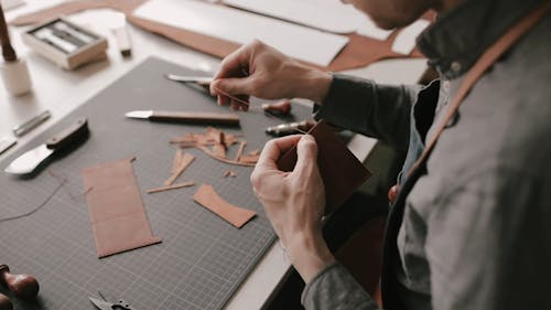 A Person Sewing a Piece of Leather