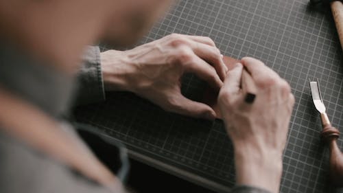 A Person Cutting a Piece of Leather