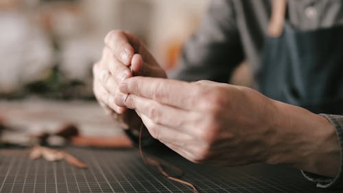 Man Putting a Brown Thread in the Needle