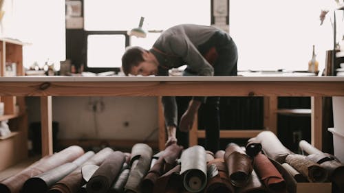 Man Putting A Roll of Leather on the Table