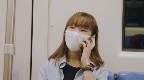 Woman Wearing White Face Mask Talking on Her Phone