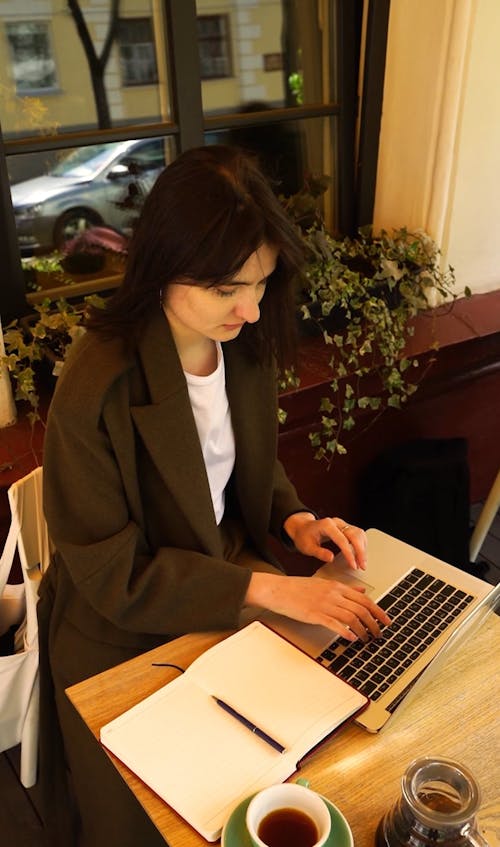Woman Typing on Her Laptop and Drinking Coffee