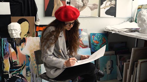 Woman Sitting on a Chair While Drawing on a White Paper