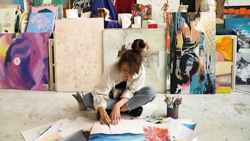 Woman Sitting on a Floor While Painting on Her Canvas