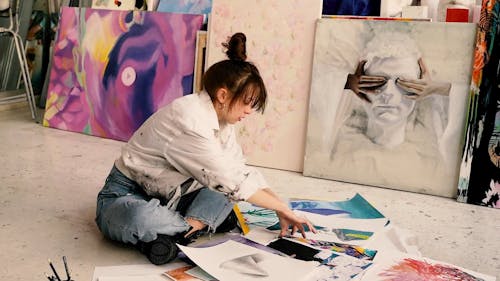 Woman Sitting on a Floor While Drawing on a White Paper