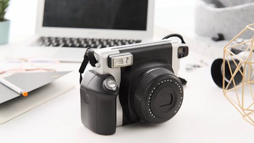 An Instant Camera and a Notebook on a Work Desk