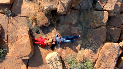 Drone Footage of Couple Lying Down on Top of Rock Mountain