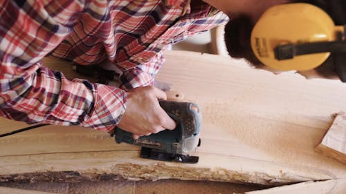 A Carpenter Cutting Away The Damaged Part Of A Wooden Board