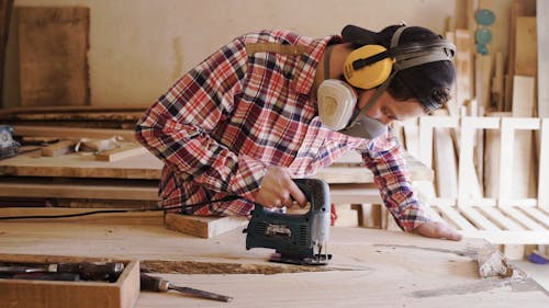 A Man Using A Power Toll To Cut A Board