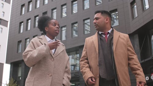 A Man And A Woman Walking In Business Suits 