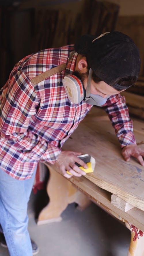 A Man Smoothing The Wood Edges Using A Sand Paper