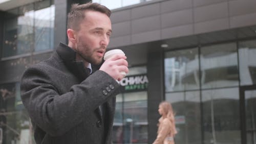 A Man Sipping Coffee while Walking