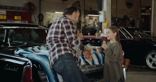 A Young Girl Joining Her Elder In Having Snack Inside A Motor Shop