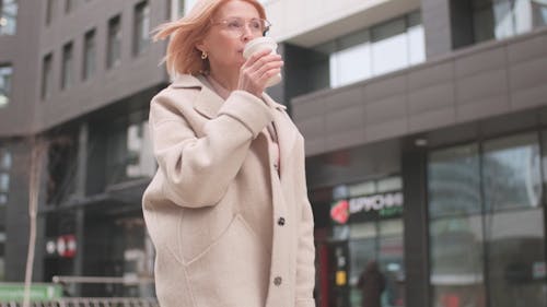 A Woman Walking With A Coffee On Hand