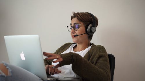 A Woman Engage In Telecommuting Using A Laptop With A Headset