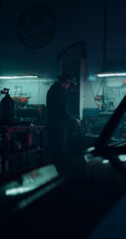 A Man Welding A Metal Piece Inside A Motor Shop