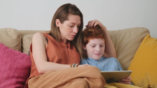 A Mother Teaching Her Son Using A Digital Tablet At Home