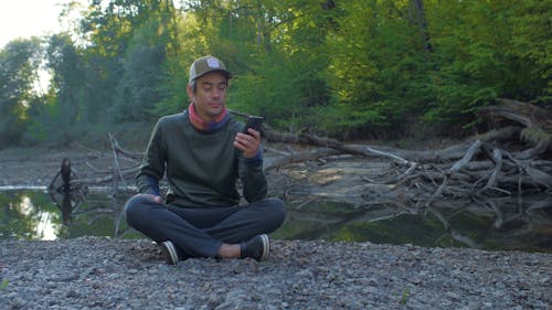 Man Sitting on The Ground Holding His Phone