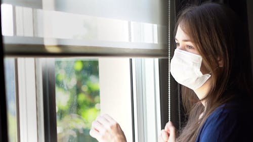 Woman Opening the Blinds of a Window