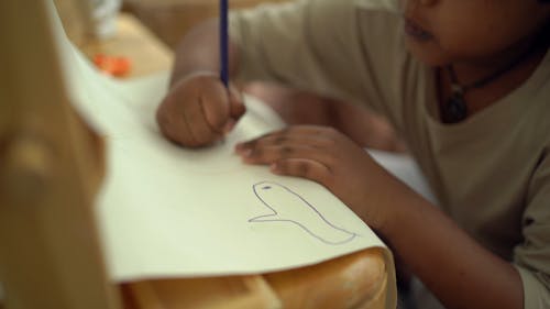 A Kid Drawing Using A Colored Pencil