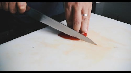 A Person Slicing Red Bell Peppers
