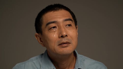A Man Crying and Wiping His Tears