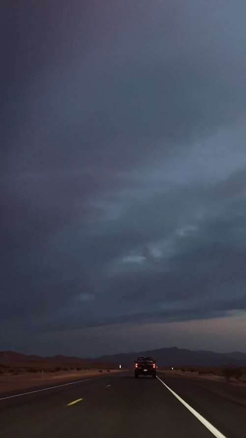 Vehicle Traveling on Roadway Under Dark Sky