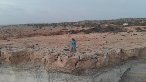 A Woman Standing on the Edge of a Cliff by the Sea