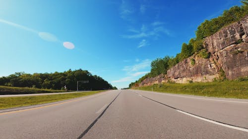 A Vehicle On The Road Traveling Under A Blue Sky