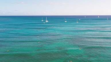 people swimming on the beach near boats
